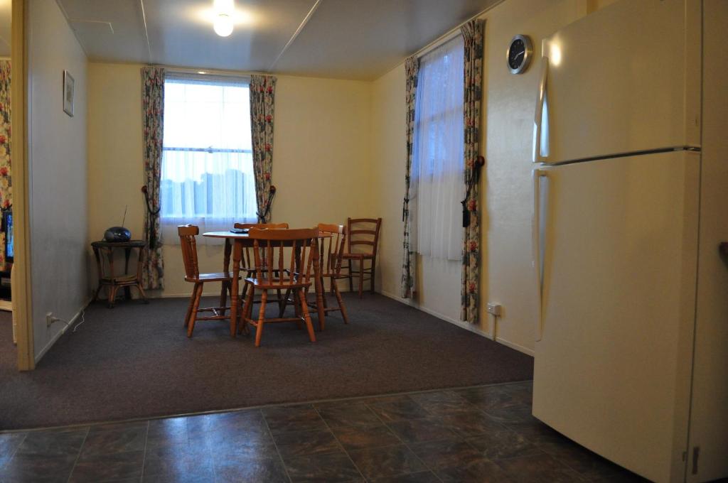 a kitchen with a table and chairs and a refrigerator at GreenGate Cottages in Strahan