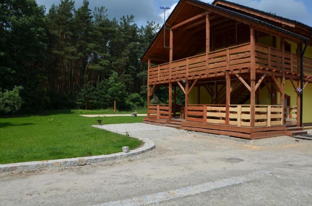 un grand bâtiment en bois avec une pelouse et des arbres dans l'établissement Agroturystyka U Siwego, à Rokitki