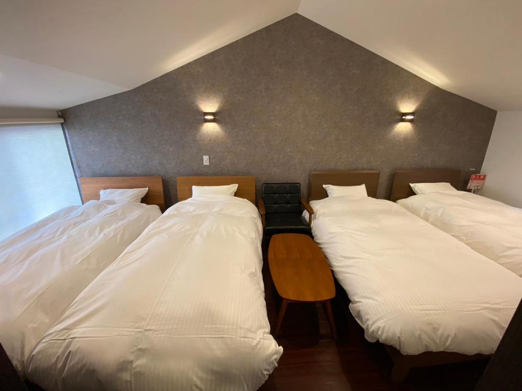 eine Gruppe von 3 Betten in einem Zimmer in der Unterkunft Yuzenkyo in Kyoto