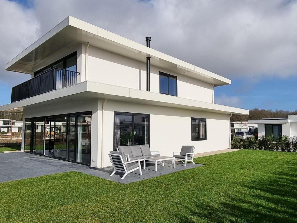 a white house with two chairs and a table at Nice water villa near forest, golf course and Veluwemeer in Zeewolde