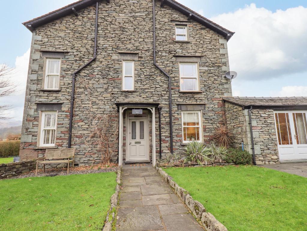 a stone house with a door and a grass yard at Honeywood House in Grasmere