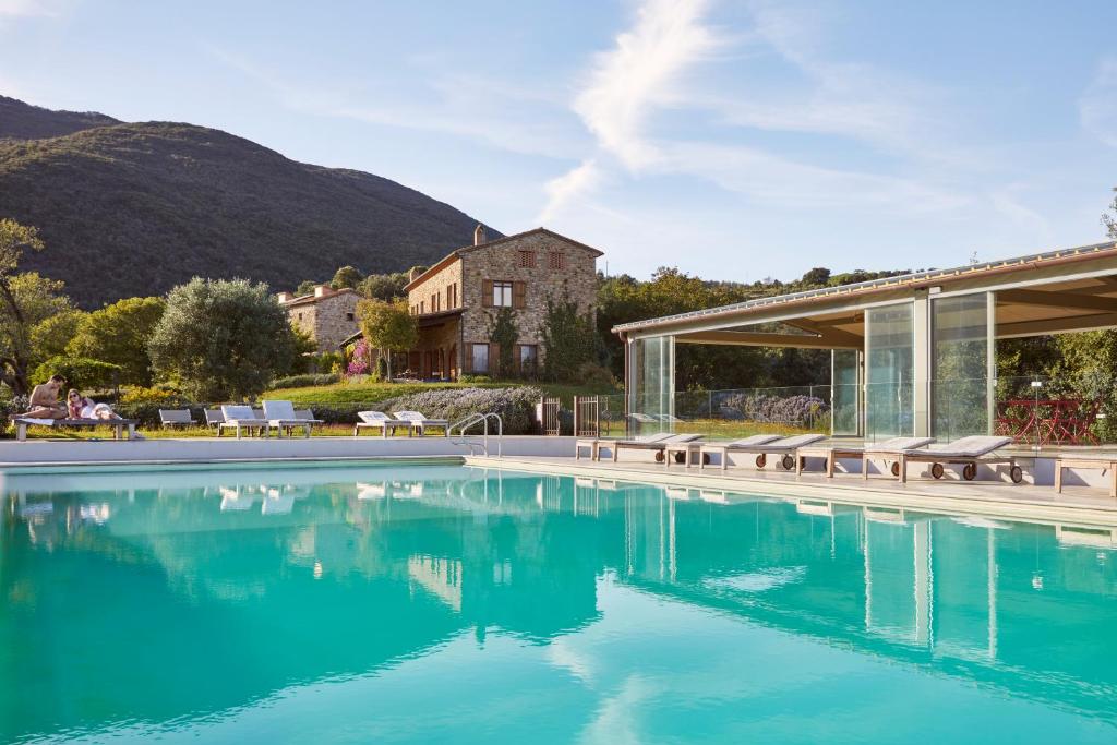 a swimming pool with a house and mountains in the background at Agriturismo Boschi di Montecalvi in Suvereto
