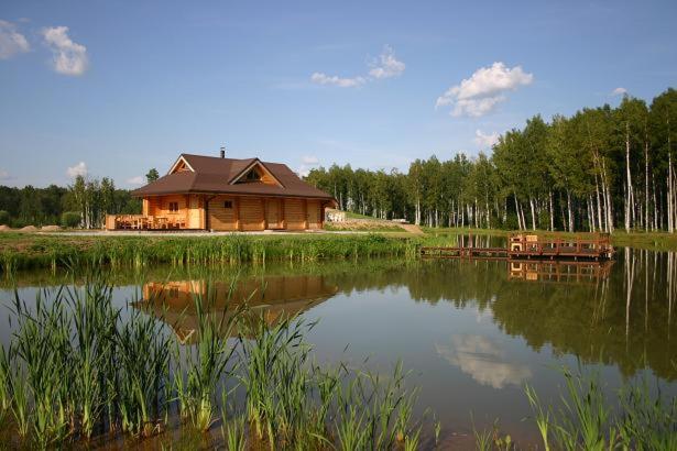 una baita di tronchi situata accanto a un lago di Pirts ēka ar pirti a Jumpravmuiža