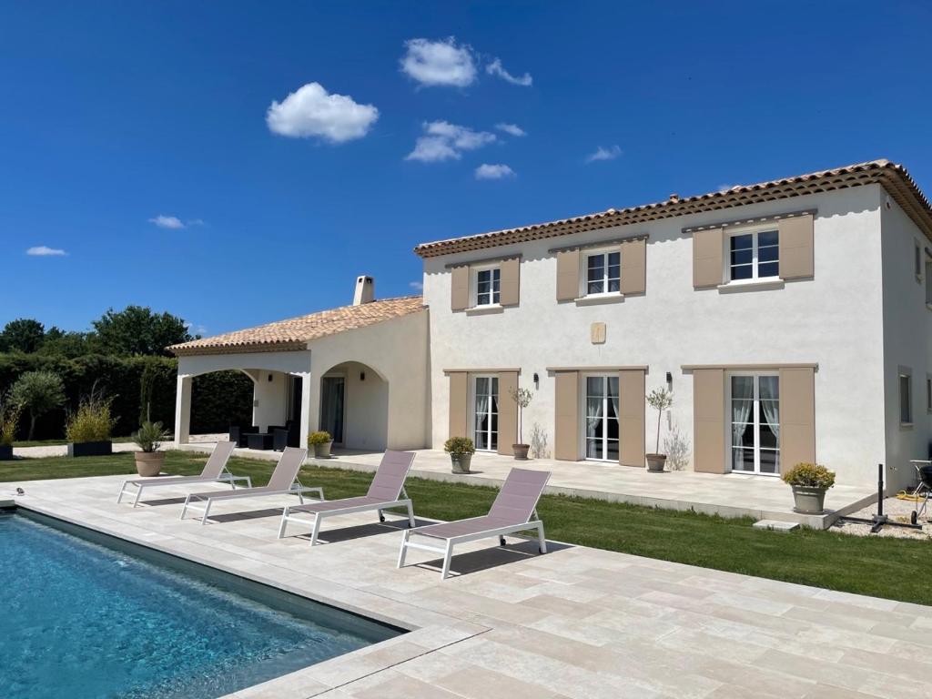 a villa with a swimming pool in front of a house at La Bastide Cezanne Natural elegance in Aix-en-Provence