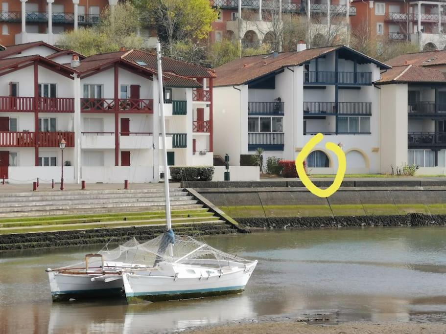 un bateau dans l'eau à côté de certains bâtiments dans l'établissement PAYS BASQUE BAIE SOCOA CIBOURE ST JEAN DE LUZ, à Ciboure