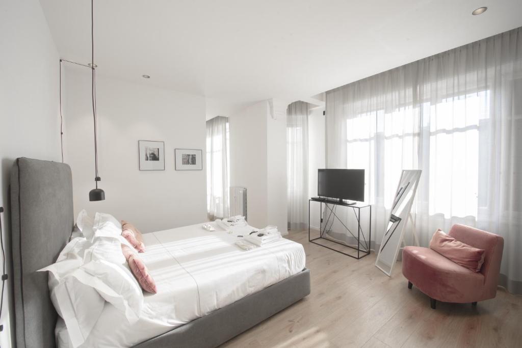 biała sypialnia z łóżkiem i krzesłem w obiekcie San Carlo Suite Torino w Turynie