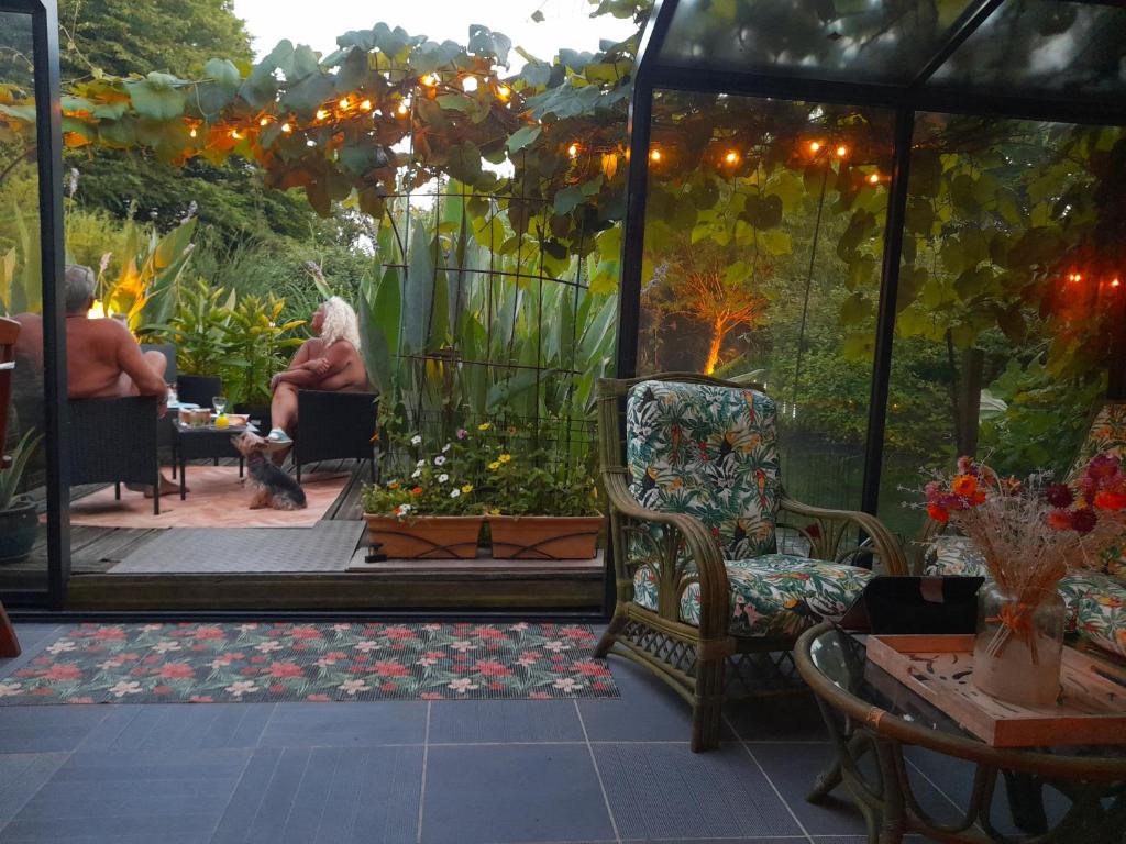 une femme assise dans un kiosque dans un jardin dans l'établissement chambres d'hôtes naturistes de la moque souris, à Saint-Pierre-de-Mailloc