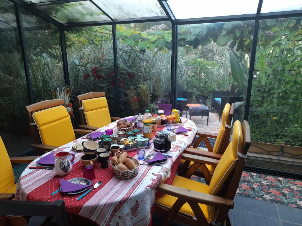 a table with food on it in a greenhouse at chambres d'hôtes naturistes de la moque souris in Saint-Pierre-de-Mailloc