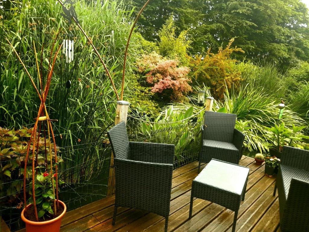 a deck with chairs and a table and some plants at chambres d'hôtes naturistes de la moque souris in Saint-Pierre-de-Mailloc
