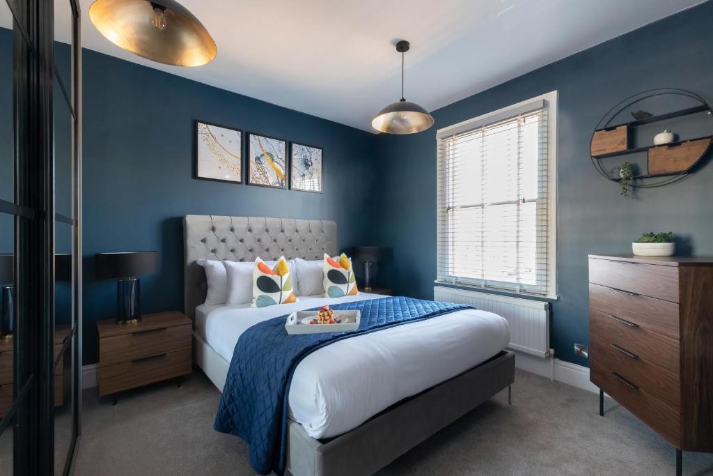 a blue bedroom with a bed with a tray on it at Elliot Oliver - Laverham House - Stunning 6 Bedroom Regency House With Parking in Cheltenham