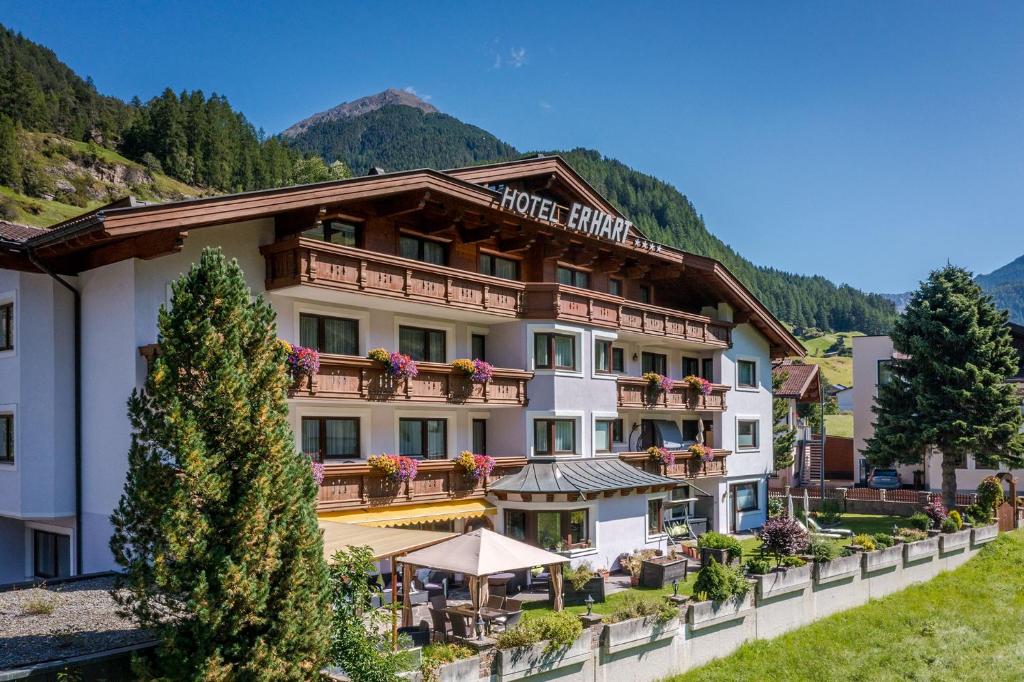 un hôtel dans les montagnes avec des tables et des parasols dans l'établissement Hotel Erhart Sölden inklusive Summer Card, à Sölden