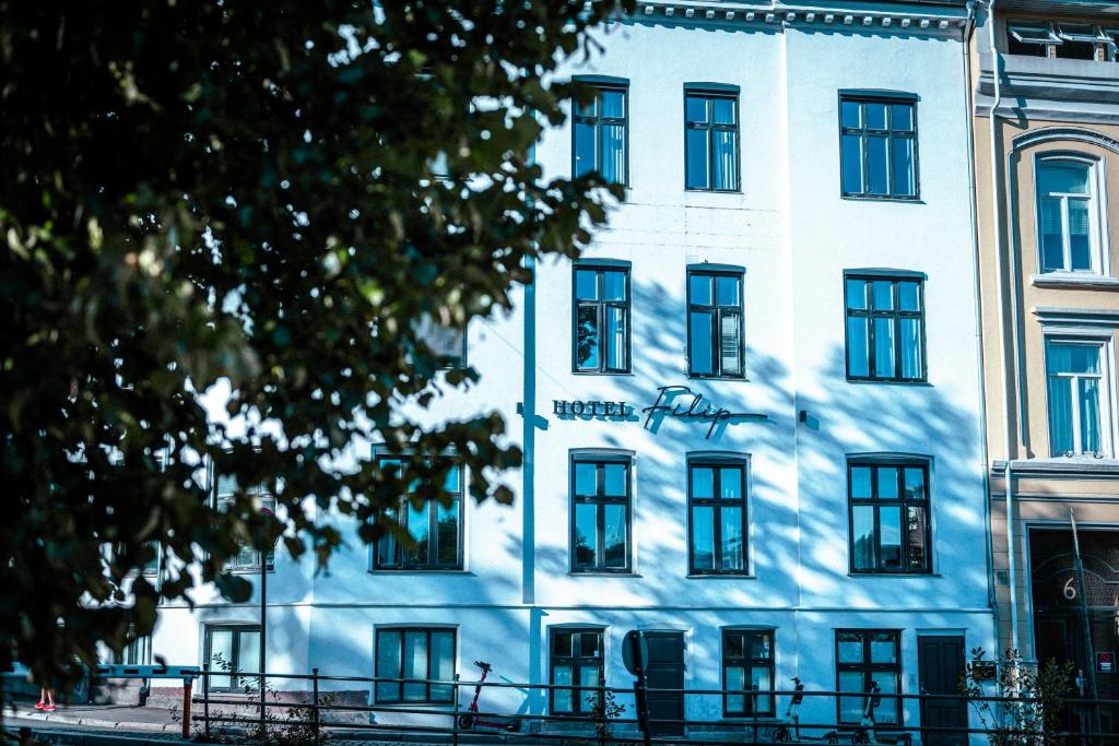 a blue building with black windows and a tree at Hotel Filip in Oslo