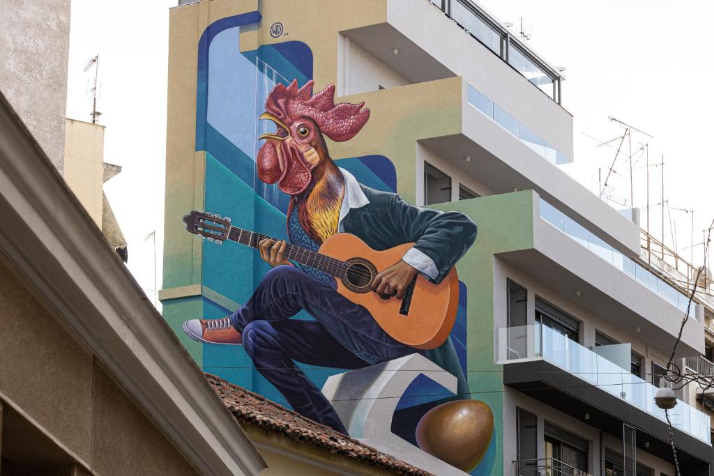 a mural of a rooster holding a guitar on a building at The Rooster's Egg in Athens