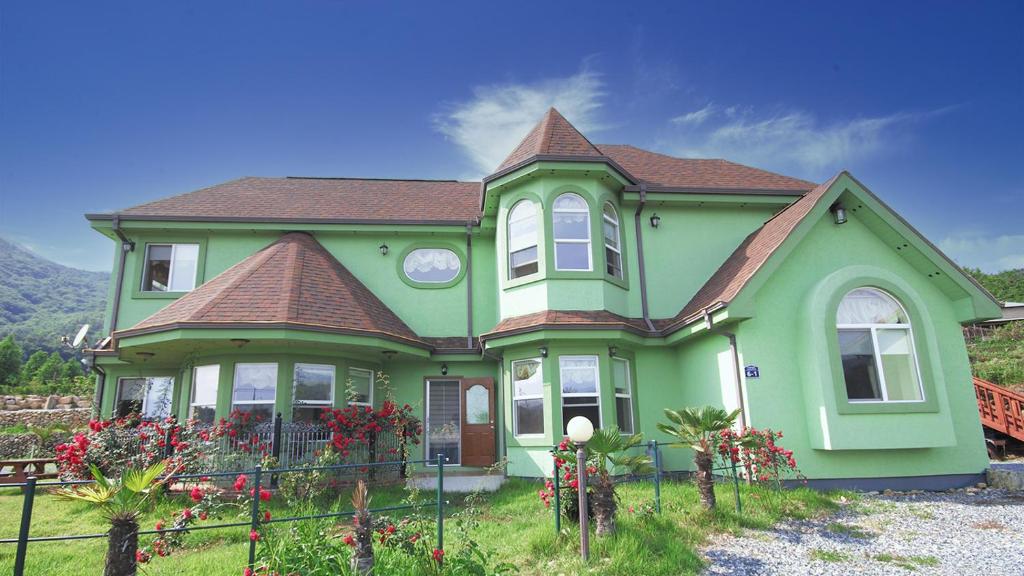 een groen huis met een bruin dak bij Ever Rose Pension in Namhae