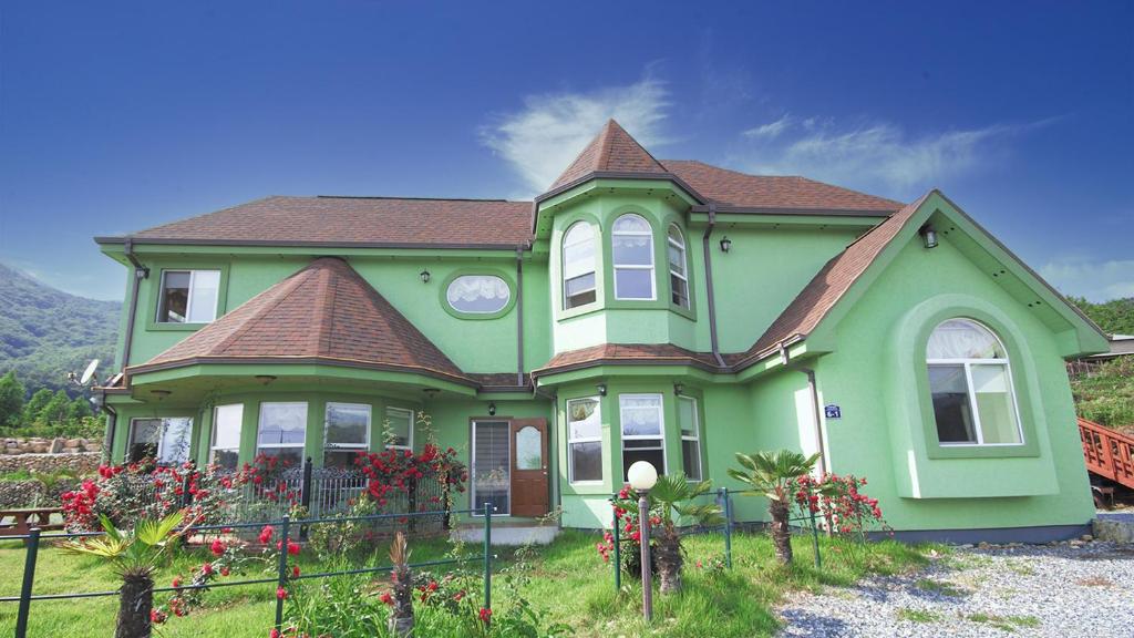 a green house with a brown roof at Ever Rose Pension in Namhae