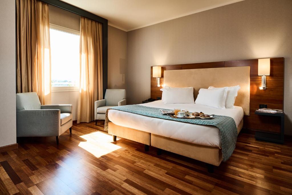 ein Hotelzimmer mit einem Bett und einem Stuhl in der Unterkunft Hotel Da Vinci in Vinci