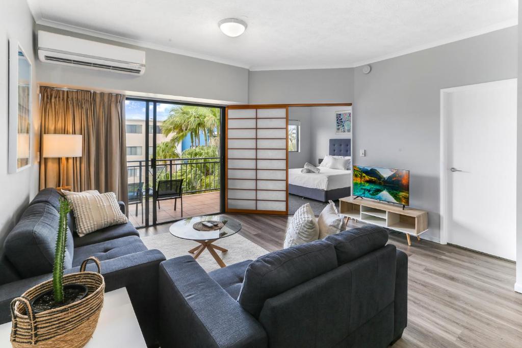 un salon avec des canapés bleus et une chambre dans l'établissement Unit 41 at Portobello Dicky Beach, à Caloundra