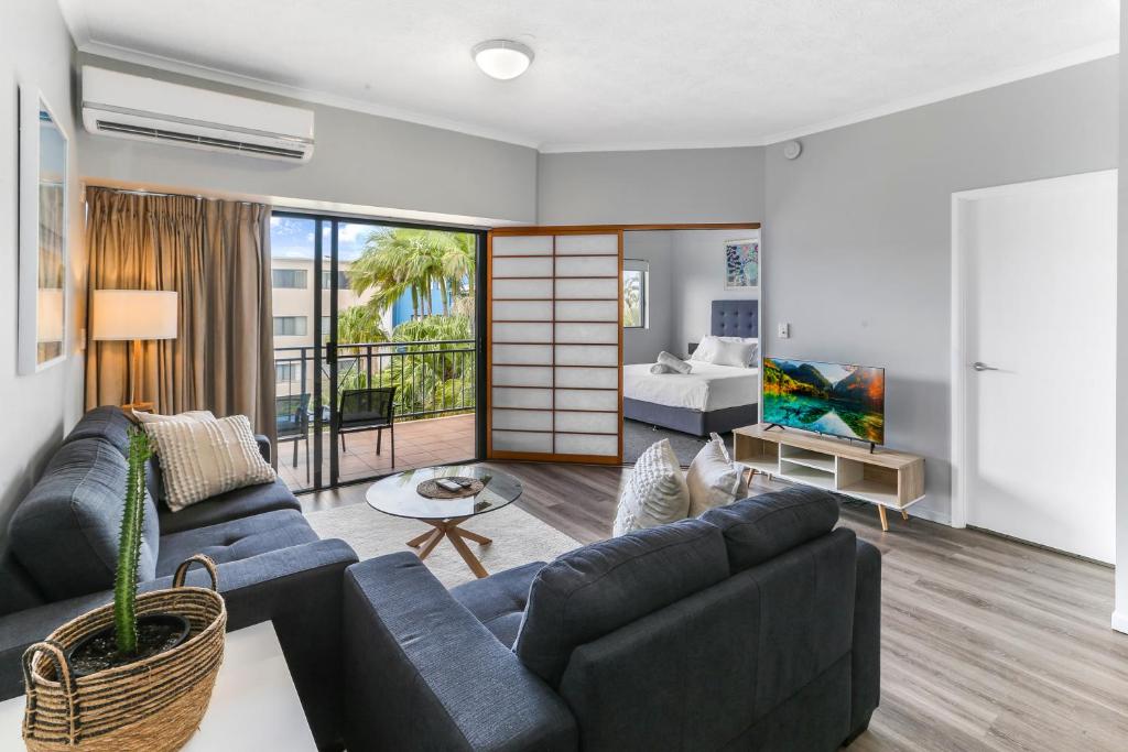 a living room with blue couches and a bedroom at Unit 41 at Portobello Dicky Beach in Caloundra