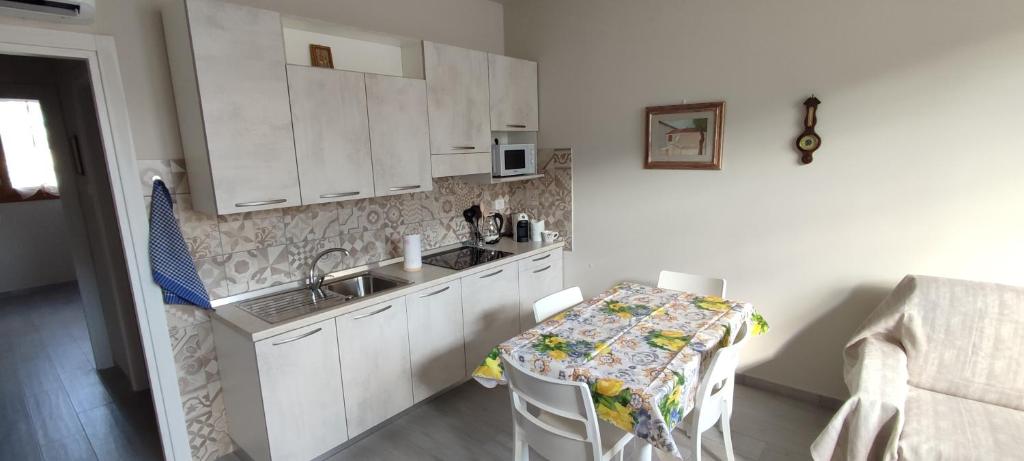 uma cozinha com armários brancos, uma mesa e um lavatório em Valdisieve Guest House Appartamento 20 minuti da Firenze em Pontassieve