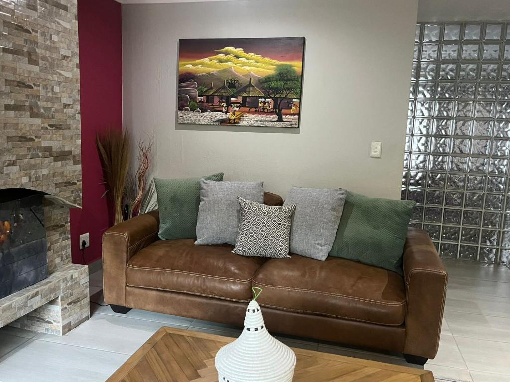 a brown leather couch in a living room with a painting at Rosa on St James in Johannesburg