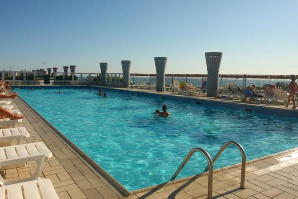 a large swimming pool with people in the water at Homely flat with balcony and swimming pool in Bibione