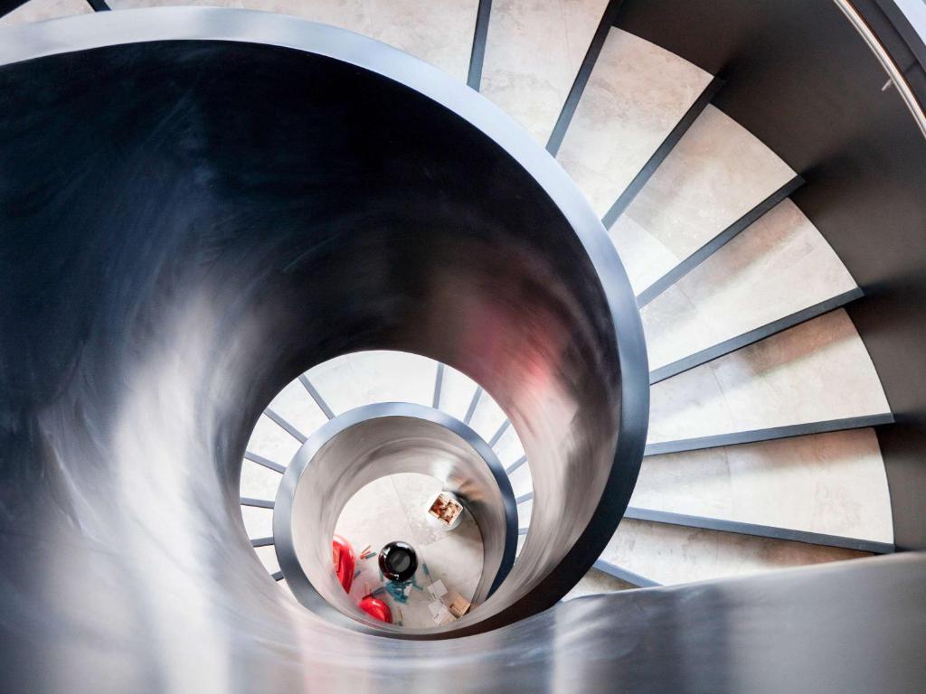 a spiral staircase in a building with people walking down it at Novotel Auckland Airport in Auckland