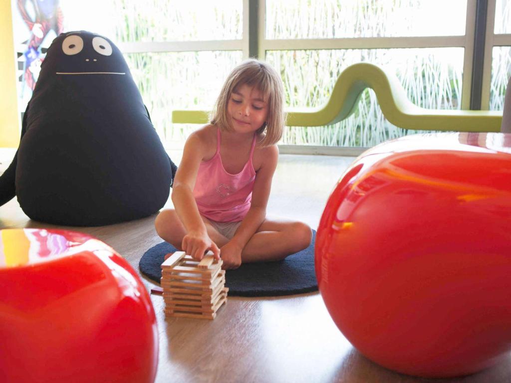 a little girl playing with a wooden toy at Novotel Auckland Airport in Auckland