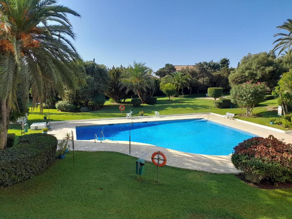 a large swimming pool in a park with palm trees at Apartment with pool near the beach in Marbella