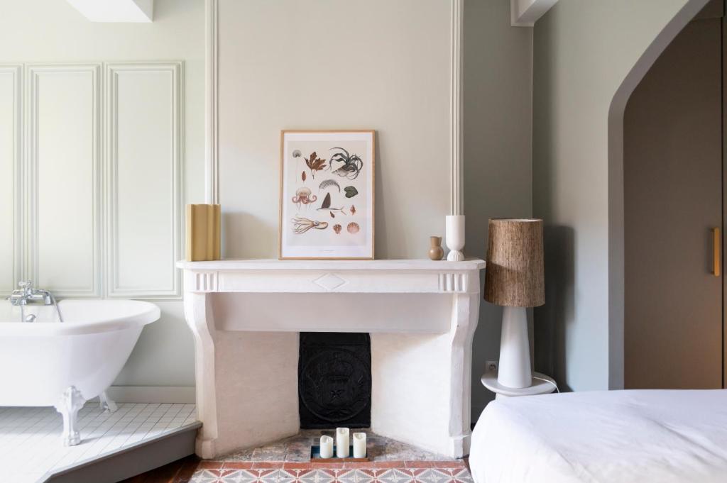 a white bathroom with a fireplace and a sink at Séjours Maison Baluchon in Chaumont