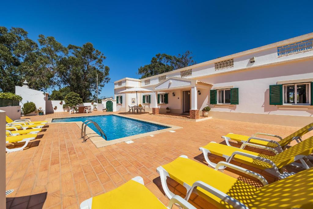 une villa avec une piscine et des chaises longues jaunes dans l'établissement Casa da Bia by OCvillas, à Albufeira