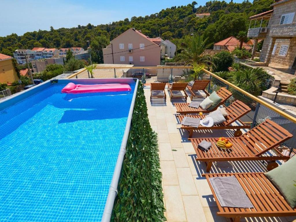 una piscina con un montón de sillas al lado en Palm Tree Apartments en Dubrovnik