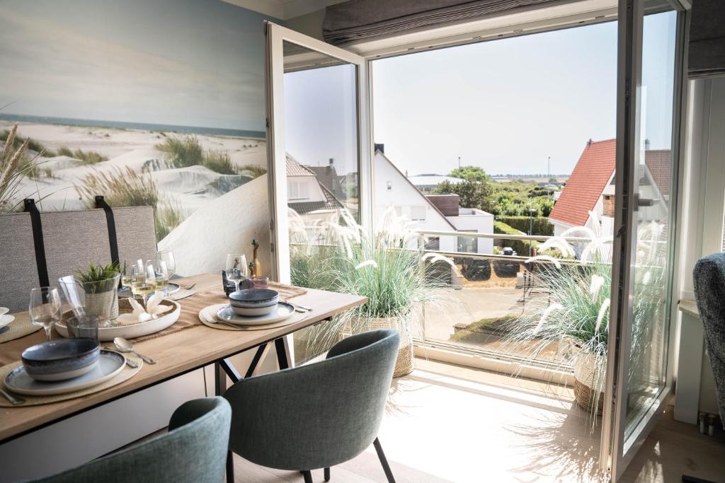 uma sala de jantar com mesa e cadeiras e vista para a praia em Rising Sun Westende em Middelkerke