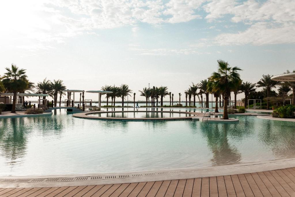 a swimming pool with palm trees in a resort at ERTH Abu Dhabi Hotel in Abu Dhabi