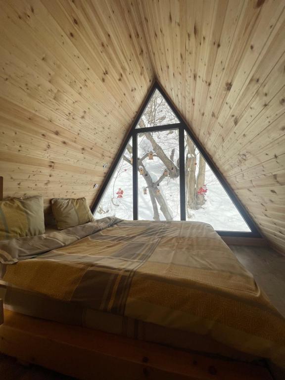 a bed in a wooden room with a large window at Aroa Mountain 4 in Zărneşti