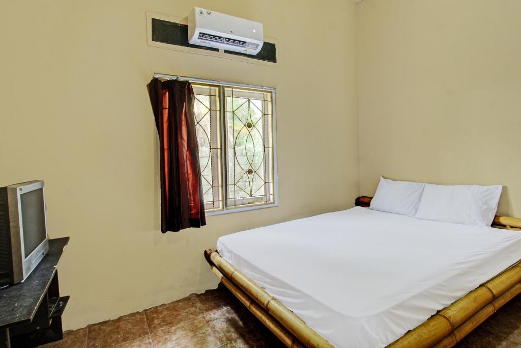1 dormitorio con cama y ventana en OYO 92197 Zahira Homestay, en Ekas