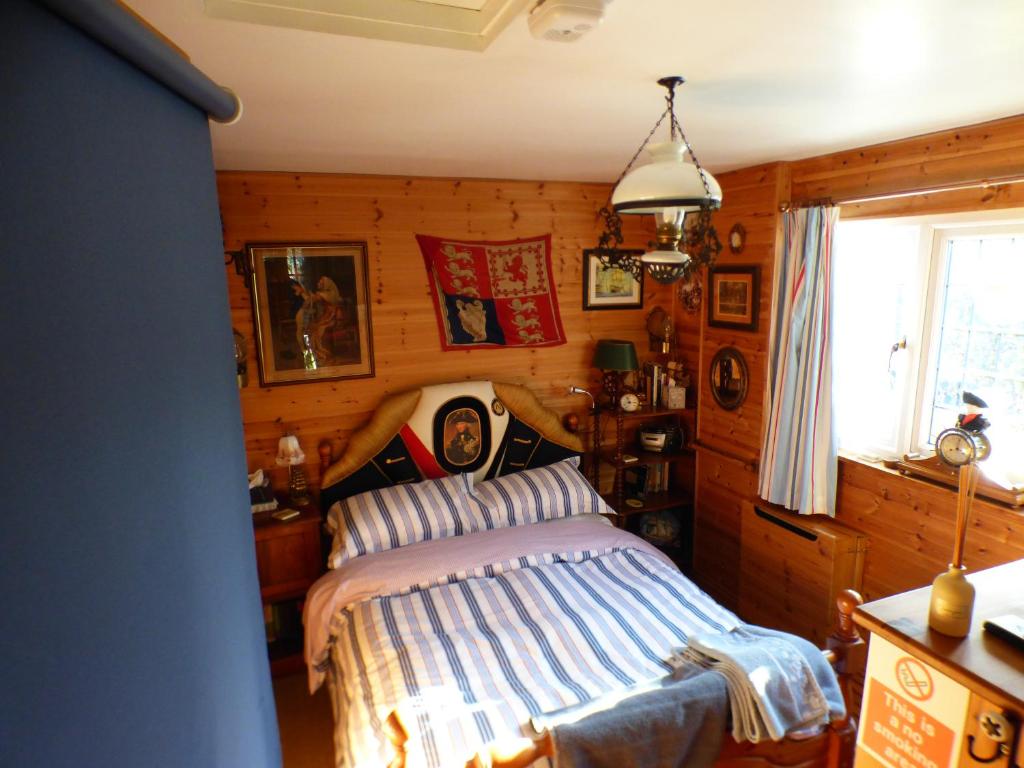 a bedroom with a bed in a room with wooden walls at NELSONS CABIN in North Creake