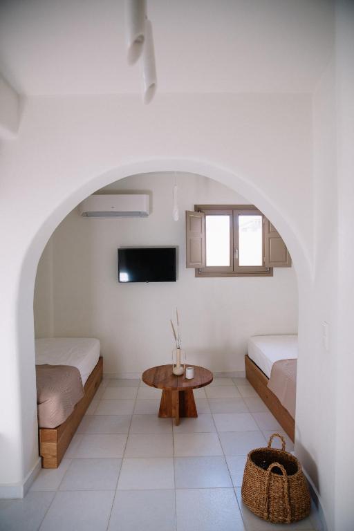 a white room with two beds and a table at Ammothines Cycladic Suites in Naxos Chora