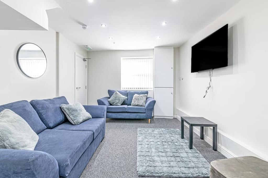 a living room with a blue couch and a tv at Luxury 5 Bedroom Holiday Home Within Prescot in Prescot