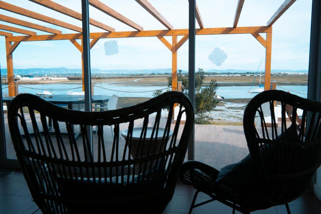 two chairs sitting on a porch looking out at the ocean at Wax Hostel in Faro