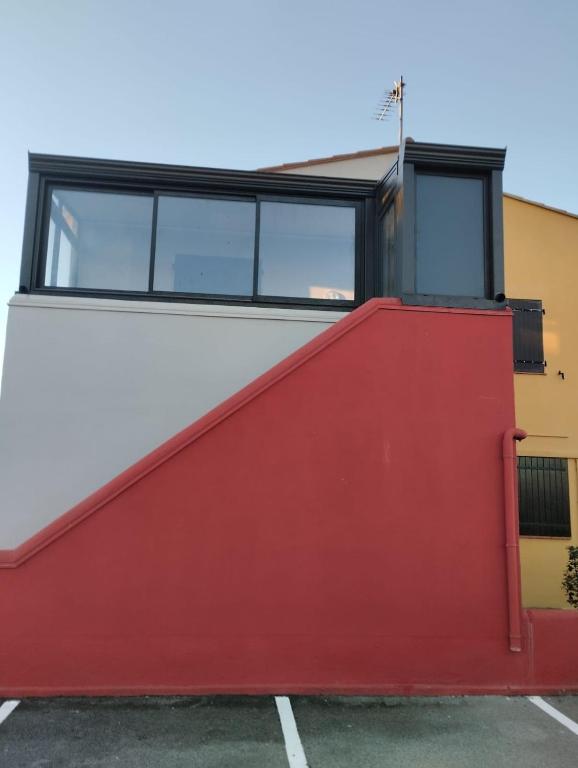 Maison rouge et blanche avec fenêtre dans l'établissement Appartement 100 mètres plage avec parking privé, au Barcarès