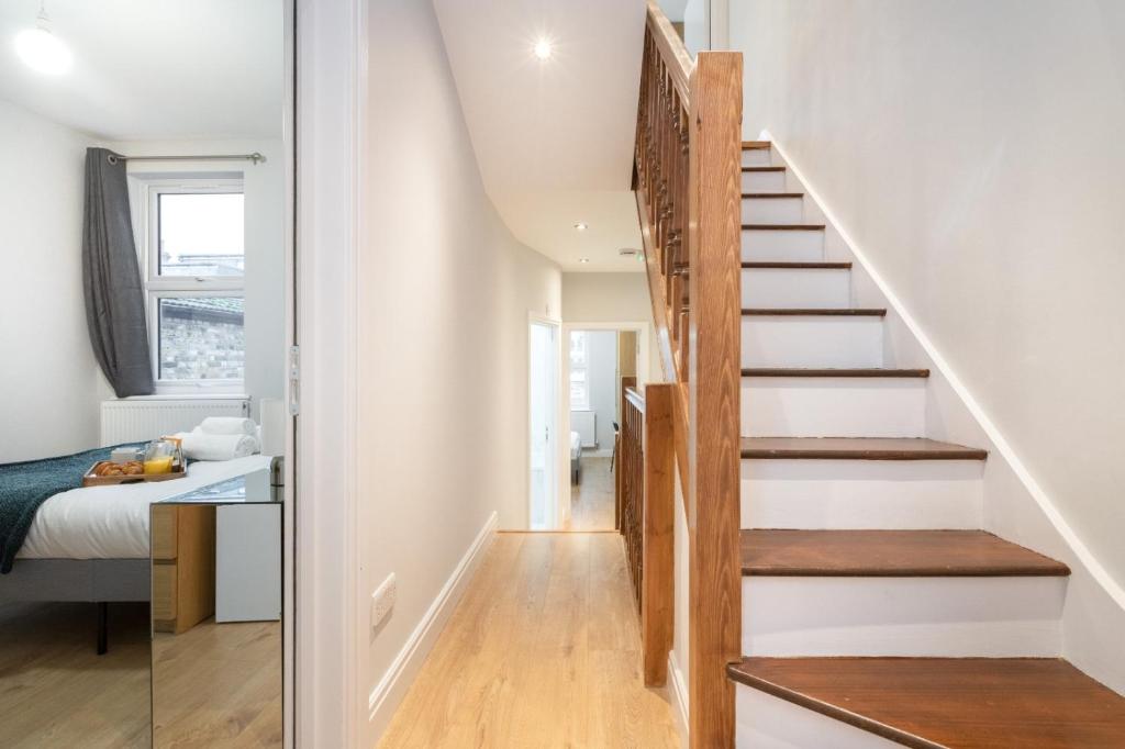 a staircase in a house with white walls and wooden floors at Spacious apartment near Hammersmith staion in London