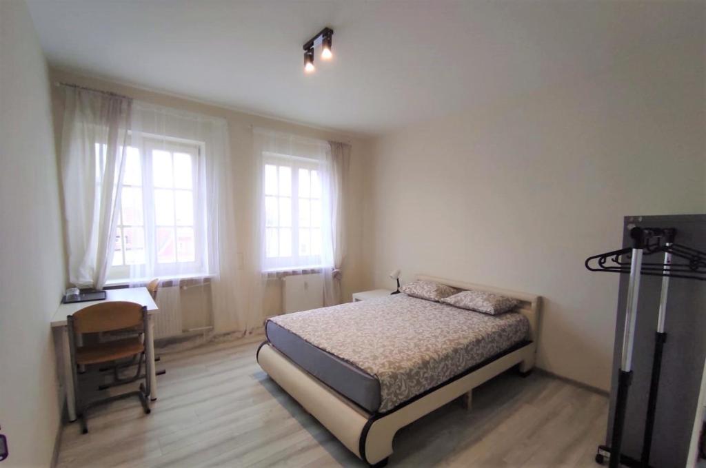 a bedroom with a bed and a desk and two windows at Rynek 9 in Poznań