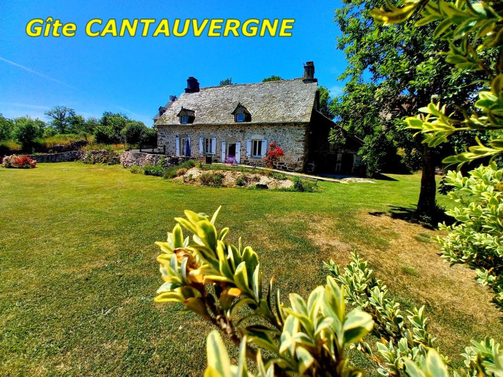 an old stone house in a field with a yard at Gite CANTAUVERGNE in Vebret