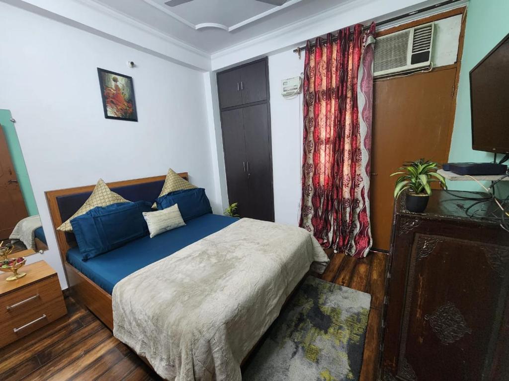 1 dormitorio con cama con sábanas azules y ventana en Homlee-Best Value flat with kitchen Near Metro, en Nueva Delhi
