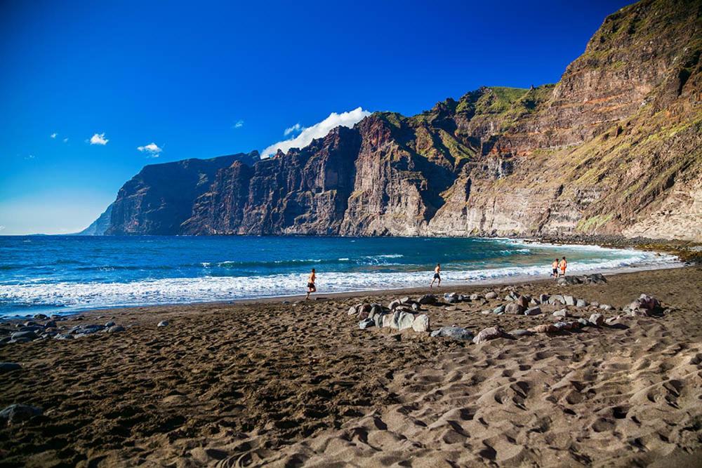personnes sur une plage avec une montagne en arrière-plan dans l'établissement BuenaVista Gigantes Marina, à Acantilado de los Gigantes