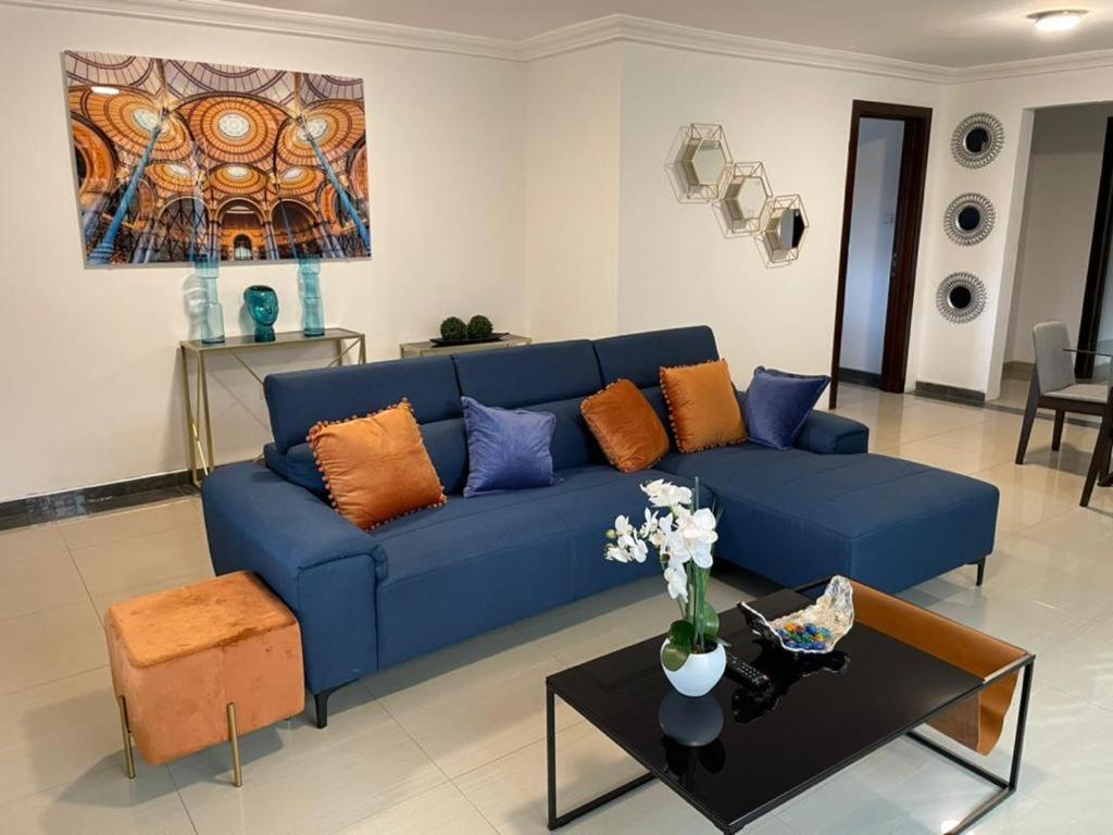 ein blaues Sofa im Wohnzimmer mit einem Tisch in der Unterkunft Nuben Court-Accra in Accra
