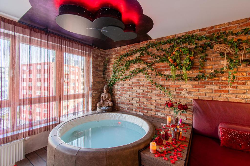 uma casa de banho com uma grande banheira numa parede de tijolos em Jacuzzi - Love - BDSM - Extra Luxury - EV chargger - Valentine's Day - Red Room - Flexible SelfCheckIns 28 em Zagreb