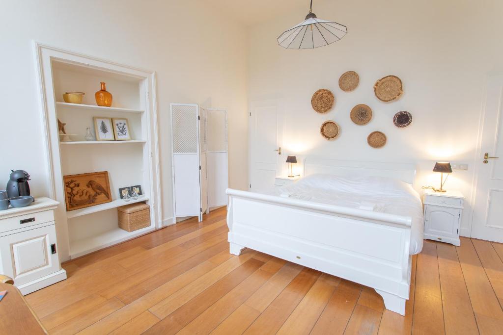 a bedroom with a white bed and a wooden floor at De Dekenije in Zutphen