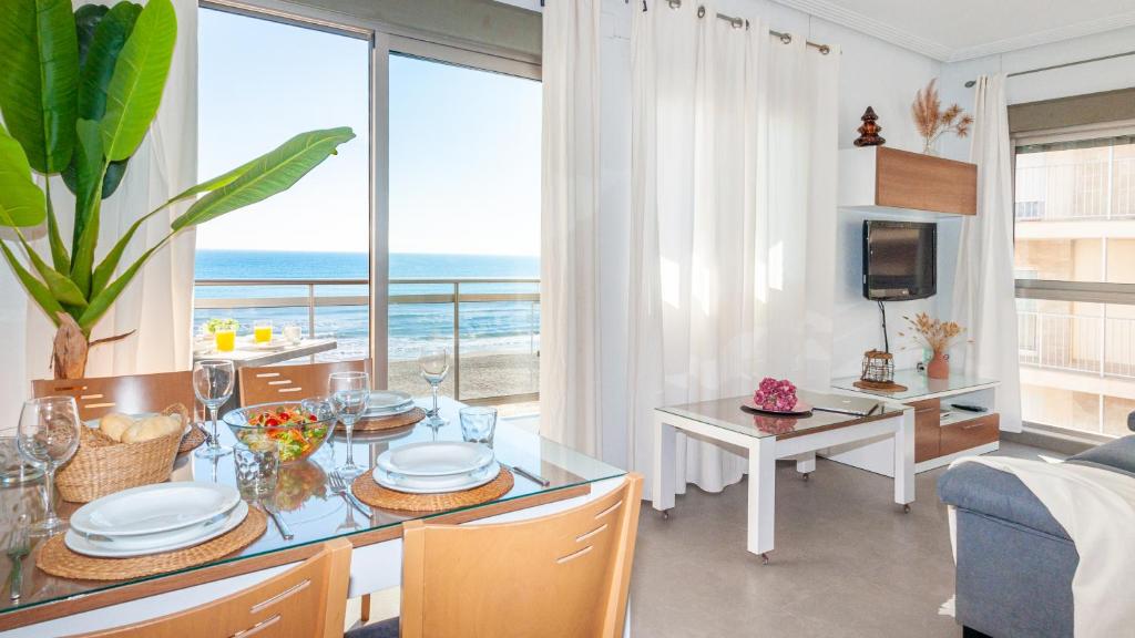 a dining room and living room with a view of the ocean at Apartamentos Turisticos Rent Guardamar in Guardamar del Segura