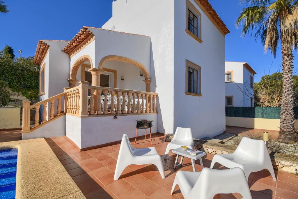 a patio with white chairs and a house at Monte Amarillo in Jávea
